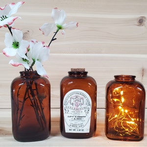 May include: Three amber glass bottles with cork stoppers. The center bottle has a label that reads "Scotch & Rappee Snuff Manufactured Levi Garrett & Sons 120 & 122 Front Street Philadelphia Net Wt. 5.58 oz."