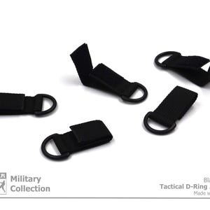 Może przedstawiać: Pięć czarnych taktycznych adapter&oacute;w z k&oacute;łkiem D. Adaptery wykonane są z czarnego paska z czarnym metalowym k&oacute;łkiem D. Tekst "Black Color Tactical D-Ring Adapter Made with Passion" jest wydrukowany pod obrazkiem.