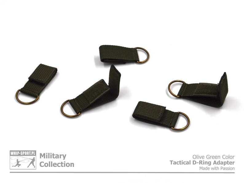 Pode incluir: Cinco adaptadores t&aacute;ticos de anel em D de cor verde oliva com an&eacute;is de lat&atilde;o. Os adaptadores s&atilde;o feitos de fita e t&ecirc;m um fecho de velcro. "Olive Green Color Tactical D-Ring Adapter Made with Passion" est&aacute; impresso em um fundo branco abaixo dos adaptadores.