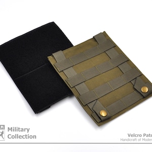 Può includere: Un pannello di velcro verde con un retro in velcro nero. Il pannello ha una griglia di cinghie per fissare le patch. Il testo "Velcro Patch Panel" e "Handicraft of Modern Evolution" è stampato sotto il pannello.