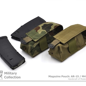 Op de afbeelding: Drie magazijnzakken in verschillende camouflagepatronen: groen en bruin, zwart en groen en effen groen. De zakken zijn gemaakt van duurzaam materiaal en hebben een klep sluiting. De tekst "Magazine Pouch: AR-15 / M4 / GROT" is onder de zakken gedrukt. De tekst "Handicraft of Modern Evolution" is onder de eerste regel tekst gedrukt.
