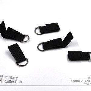 Pode incluir: Cinco adaptadores t&aacute;ticos de anel em D pretos com fecho de velcro. Cole&ccedil;&atilde;o Militar. Cor preta. Adaptador t&aacute;ctico de anel em D. Feito com paix&atilde;o.