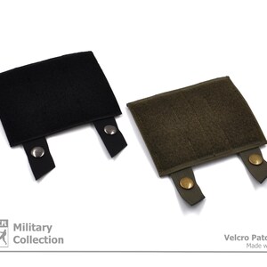 Peut inclure: Deux panneaux de patchs Velcro, un noir et un vert olive, avec des boutons pression m&eacute;talliques sur les sangles. Les panneaux sont con&ccedil;us pour fixer des patchs &agrave; l'&eacute;quipement tactique. "Military Collection" et "Velcro Patch Panel Made with Passion" sont imprim&eacute;s sur le fond blanc.