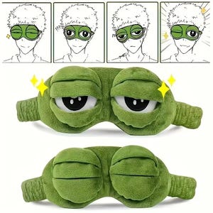 Puede incluir: Una m&aacute;scara para dormir de felpa verde con ojos blancos grandes y pupilas negras. La m&aacute;scara tiene la forma de una rana de dibujos animados con una expresi&oacute;n amplia y sonriente. La imagen tambi&eacute;n incluye una tira c&oacute;mica de cuatro paneles.