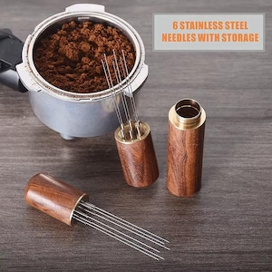 May include: A coffee distribution tool with six stainless steel needles and a wooden handle. The image also shows a portafilter filled with coffee grounds and the text "6 STAINLESS STEEL NEEDLES WITH STORAGE".