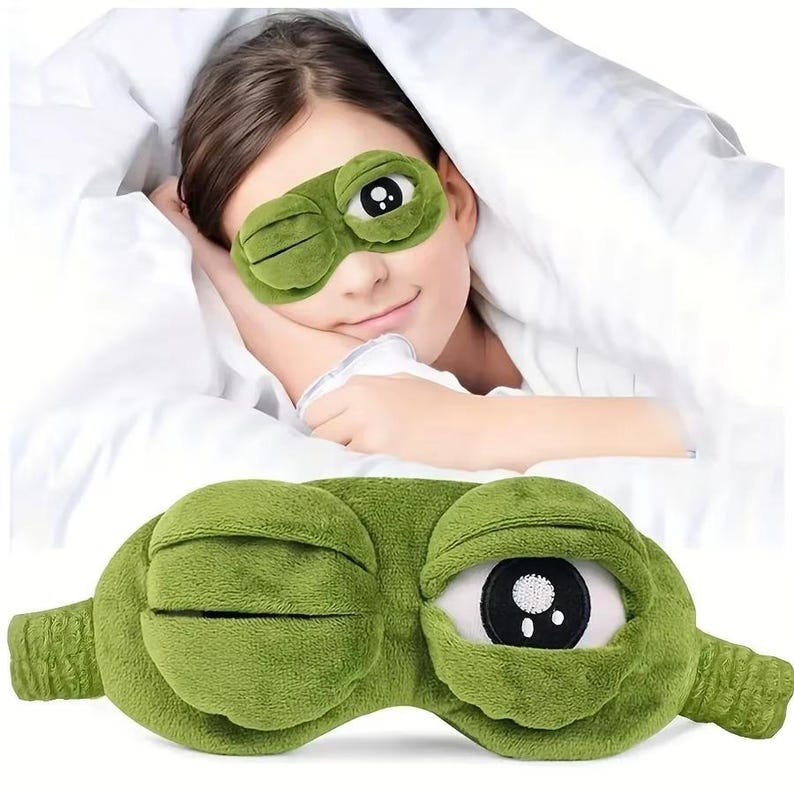 Puede incluir: M&aacute;scara para dormir verde con forma de rana, con un ojo abierto y otro cerrado. La m&aacute;scara est&aacute; hecha de un material de felpa suave. Est&aacute; dise&ntilde;ada para bloquear la luz. La m&aacute;scara se muestra en una cara y por separado.