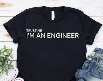 May include: A black short-sleeved t-shirt with the white text "TRUST ME I'M AN ENGINEER" printed on the chest, paired with blue denim jeans and a pair of white low-top canvas sneakers with white laces and rubber toe caps.