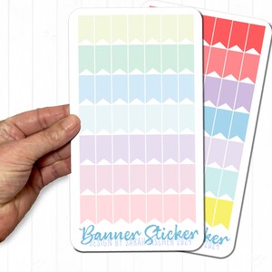 Könnte beinhalten: Zwei Stickerbögen mit Reihen farbenfroher Bannerflaggen-Designs. Ein Bogen zeigt pastellfarbene Regenbogenfarben, der andere einen Rot- bis Gelbverlauf. Der Text "Banner Stickers" und "Design by Sarah Fischer 2024" ist auf dem Pastellbogen aufgedruckt.