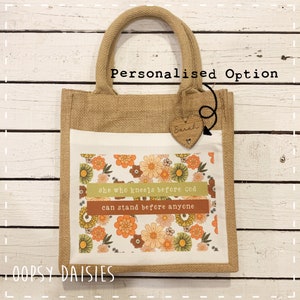 Pode incluir: Uma bolsa de juta personalizada com um design floral e a cita&ccedil;&atilde;o "Ela que se ajoelha diante de Deus pode ficar de p&eacute; diante de qualquer um". A bolsa tem um amuleto de cora&ccedil;&atilde;o de madeira com o nome "Sarah" nele. A bolsa &eacute; um &oacute;timo presente para uma ocasi&atilde;o especial.