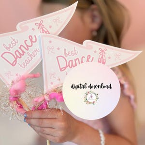 Può includere: Decorazioni per feste a forma di gagliardetto rosa e bianco con la scritta "best Dance teacher" e illustrazioni di scarpette da ballo. Le decorazioni sono adornate con piumino rosa e orpelli dorati. È visibile anche una grafica per il download digitale.