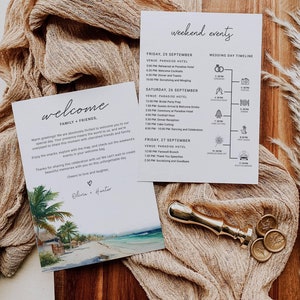 Op de afbeelding: Een welkomstbord met een tropisch strandtafereel en de tekst "Welcome Family & Friends" en "Olivia + Hunter". Het bord ligt op een houten tafel met een beige stof en een gouden waszegel.