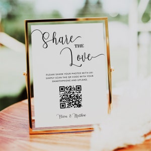 May include: White sign with black text and a QR code. The text reads "Share the Love" and "Please share your photos with us! Simply scan the QR code with your smartphone and upload." The sign is signed "Olivia & Matthew".