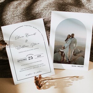 May include: Wedding invitation with a black and white arch design. The invitation reads "together with their families Olivia Bennet & William Stone joyfully invite you to their wedding Saturday September 25 20XX at three thirty o'clock in the afternoon THE GRAND ROYAL POINCIANA HOTEL BROOKLYN AVENUE, NEW YORK, NY 11215 reception to follow". A separate card features a photo of a couple in front of a rocky landscape with the text "OLIVIA + WILLIAM".