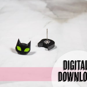 Pode incluir: Brincos de rosto de gato preto com olhos verdes. Os brincos são feitos de argila polimérica e têm um poste prateado.