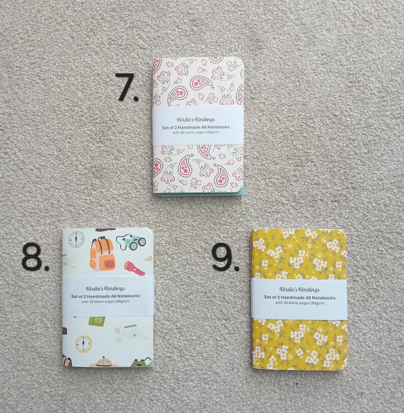 May include: Set of two A6 notebooks with paisley, floral, and camping themed covers. Each notebook has 30 blank pages. The notebooks are from Birdie's Bindings.