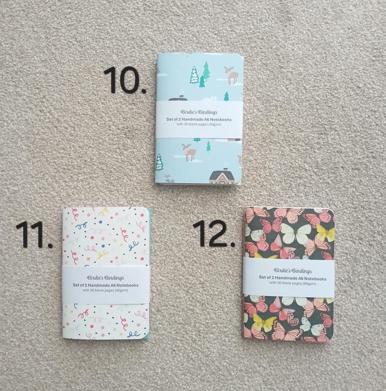 May include: Set of two A6 notebooks with 30 blank pages. The notebooks have different designs: one with a winter scene, one with a confetti pattern, and one with a butterfly pattern.