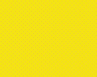 May include: Bright yellow fabric with a repeating pattern of small, light pink dots. The fabric has a ruler along the bottom edge, marked in inches. The text "Free Spirit" and "freespiritfabrics.com" are also visible.