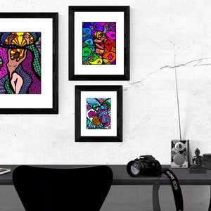 May include: Three framed abstract art prints with colorful, geometric designs. The prints are hung on a white wall with a black desk and chair in the foreground.