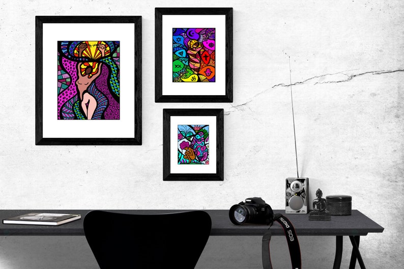 May include: Three framed abstract art prints with colorful, geometric designs. The prints are hung on a white wall with a black desk and chair in the foreground.