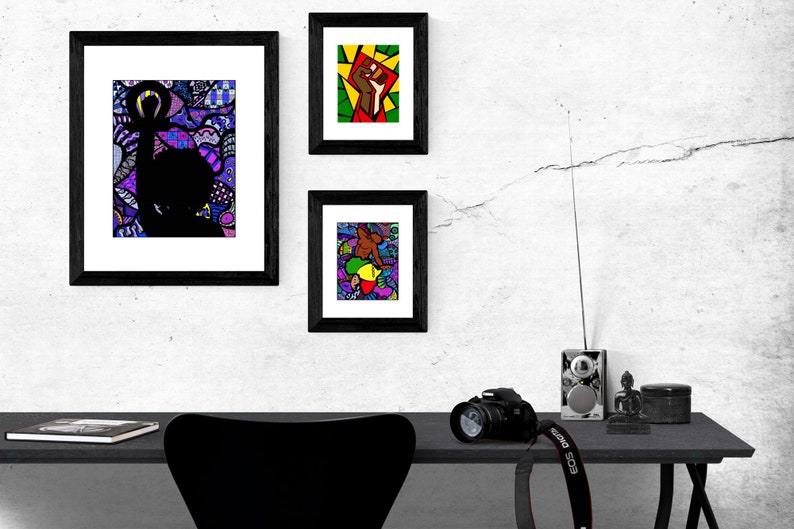 Pu&ograve; includere: Tre stampe d'arte incorniciate con disegni astratti colorati che presentano silhouette nere di persone. Le stampe sono appese a una parete bianca sopra una scrivania nera con una macchina fotografica, una radio e una piccola statua.