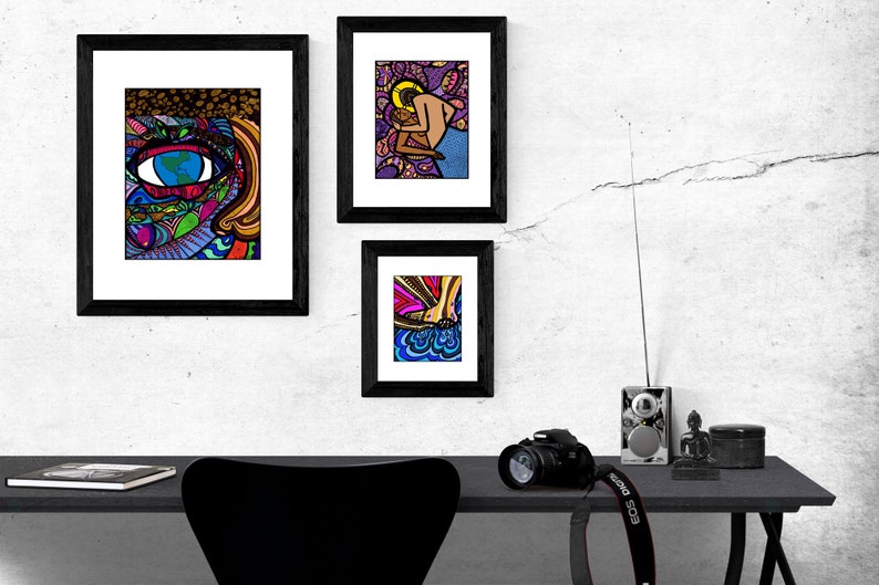 May include: Three framed illustrations with black frames and white mats. The illustrations are colorful and abstract. The top left illustration features a large eye with a world inside. The top right illustration features a couple embracing. The bottom illustration features a foot with a colorful design.
