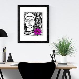 May include: Black and white line art print of a Buddha with a pink lotus flower. The print is framed in a black frame and hanging on a white wall.