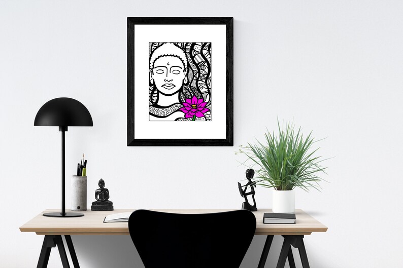 May include: Black and white line art print of a Buddha with a pink lotus flower. The print is framed in a black frame and hanging on a white wall.