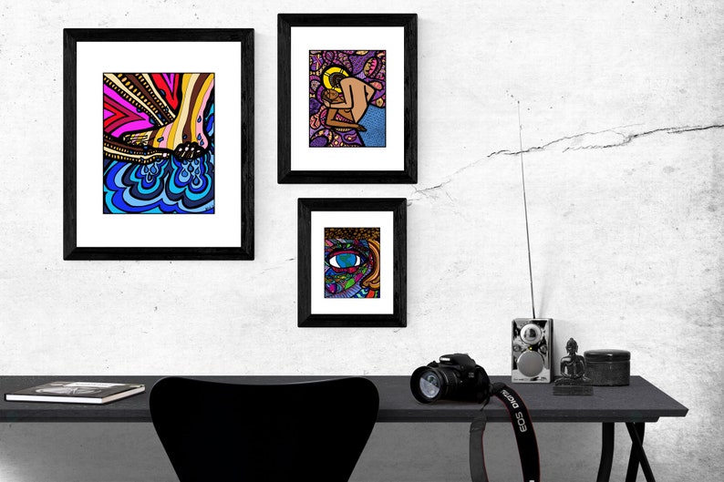 May include: Three framed illustrations with black frames hanging on a white wall. The illustrations are colorful and abstract. The top left illustration features a foot with blue and yellow water droplets. The top right illustration features a couple embracing. The bottom illustration features a colorful eye.