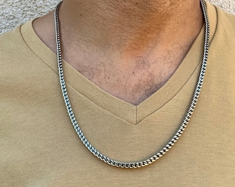 May include: A silver curb chain necklace on a person's neck.