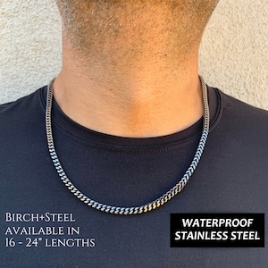 May include: A silver and black curb chain necklace made of waterproof stainless steel. The necklace is available in lengths from 16 to 24 inches.