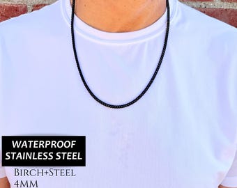 May include: A black chain necklace made of waterproof stainless steel. The chain is 4mm wide and has a black ion plating finish. The text "Waterproof Stainless Steel", "Birch+Steel", "4MM", and "Black IP Stainless Steel" is visible on the image.