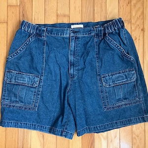 Peut inclure: Short cargo en jean bleu délavé moyen doté d'une taille élastiquée, d'une braguette zippée avec fermeture à bouton, de deux poches latérales inclinées et de deux grandes poches cargo rectangulaires sur les cuisses avec rabats et surpiqûres.