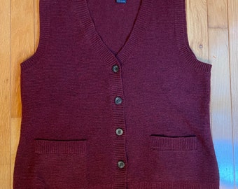 May include: A burgundy knitted vest with a V-neck, button closure, and two pockets. The vest is made by Pendleton.