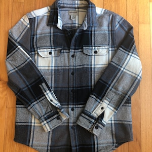 May include: A blue, white and grey plaid flannel shirt with long sleeves and a button-up front.