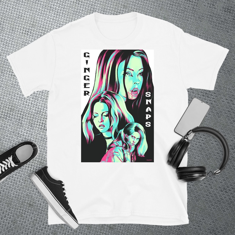 May include: White t-shirt featuring a graphic print of three women in a neon green and pink colour scheme. The text "Ginger Snaps" is printed vertically on the right side of the graphic.