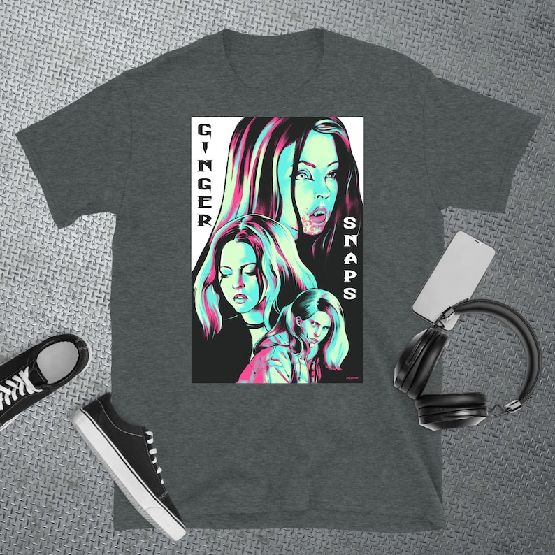 May include: A dark heather grey t-shirt featuring a graphic print of three women in a neon green and pink colour scheme. The text "GINGER SNAPS" is printed vertically on the right side of the graphic.