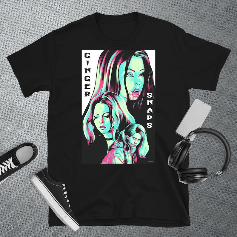 May include: Black t-shirt featuring a graphic print of three women with pink and blue accents. The text "Ginger Snaps" is printed vertically on the left side of the graphic.