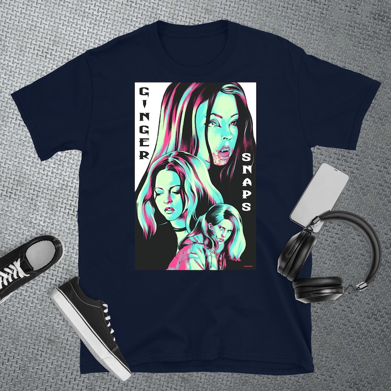 May include: A navy blue t-shirt featuring a graphic print of three women with pink and blue accents. The text "Ginger Snaps" is printed vertically on the right side of the graphic.