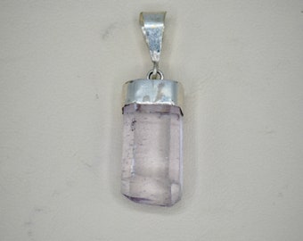 May include: A silver pendant with a clear, light purple crystal in a rectangular shape.