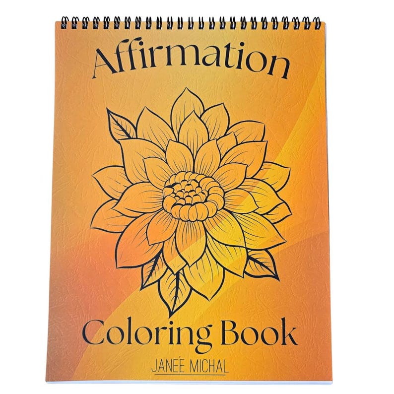 May include: A spiral bound coloring book with an orange and yellow gradient cover. The cover features a black and white illustration of a large flower with the text "Affirmation Coloring Book" and "JANEE MICHAL".