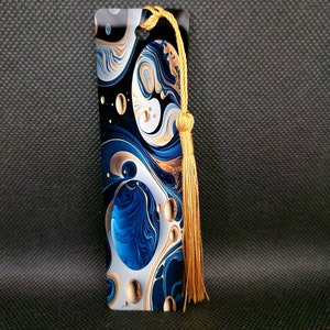 K&ouml;nnte beinhalten: Rechteckiger Lesezeichen mit einem wirbelnden abstrakten Design in Blau, Wei&szlig; und Gold. Das Lesezeichen hat eine goldene Quaste oben. Das Design zeigt eine Mischung aus organischen Formen und Mustern, die eine visuell ansprechende &Auml;sthetik erzeugen.