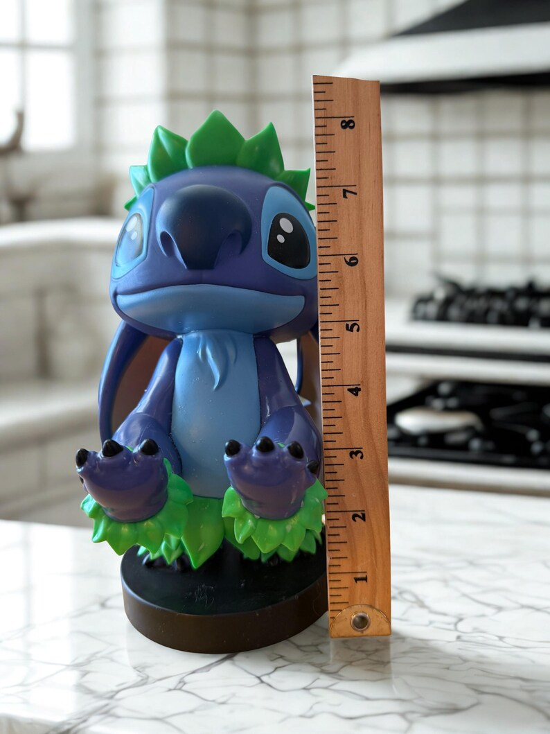 Puede incluir: Una figura azul y morada de un personaje de dibujos animados con orejas grandes y detalles verdes. La figura mide aproximadamente 20 cm de altura y se apoya sobre una base negra. El personaje tiene ojos grandes y una expresi&oacute;n amigable.
