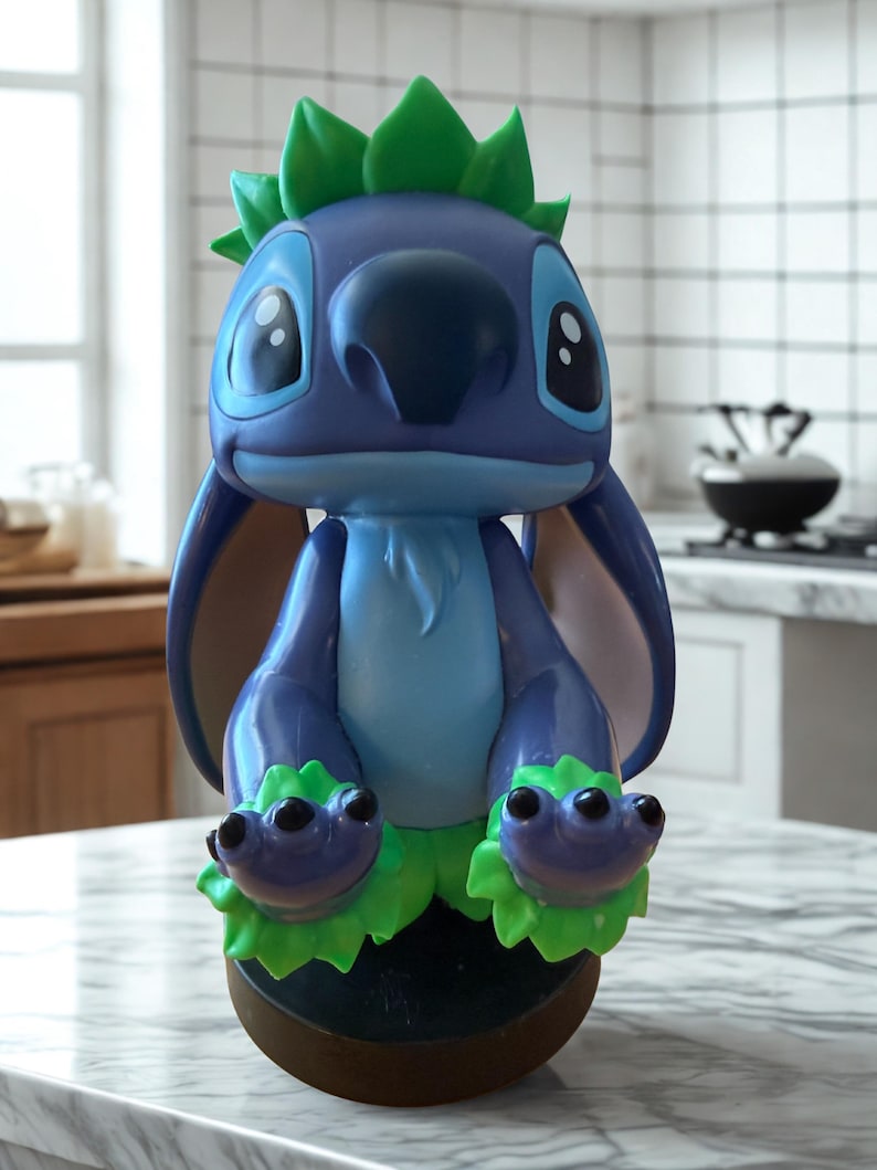Puede incluir: Figura de Stitch azul y verde. La figura tiene ojos negros grandes, una nariz grande y detalles verdes en la cabeza y los pies. La figura est&aacute; sobre una base marr&oacute;n.