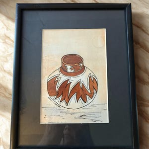May include: Framed watercolour painting of a brown and white vase with a distinctive zigzag pattern. The artwork is set against a beige backdrop and framed in a black frame. The artist's signature is visible in the lower left corner.