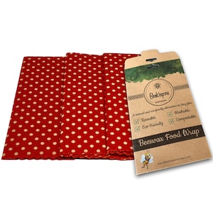 Puede incluir: Tres envoltorios de alimentos de cera de abeja de lunares rojos y blancos con una etiqueta de embalaje de cartón marrón que dice "Beekeepers Beeswax Food Wrap" y enumera los beneficios del producto: reutilizable, lavable, ecológico y compostable.