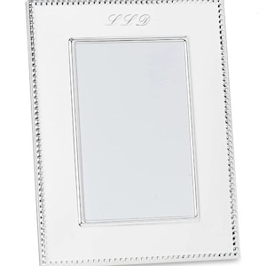 May include: A rectangular silver picture frame with a beaded border. The frame has a polished finish and a rectangular opening for a photo. The initials "LSD" are engraved at the top. A classic design for displaying cherished memories.