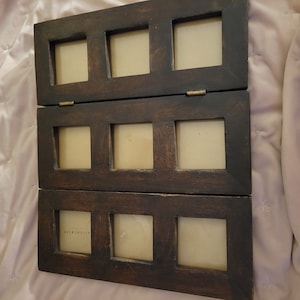 May include: A dark brown, hinged wooden photo frame with six square openings. The frame is made of stained wood and has a rustic appearance. The frame is designed to hold multiple photos and can be folded for storage or display.