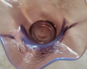 May include: A purple glass bowl with a ruffled edge and a floral design. The bowl is made of iridescent glass and has a vintage look.