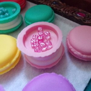 May include: A collection of six pastel-colored macarons with various fillings. Some macarons have a clear top with colorful candies inside.