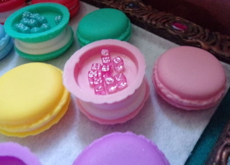 May include: A collection of six pastel-colored macarons with various fillings. Some macarons have a clear top with colorful candies inside.